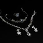 Elegant diamond jewelry set including necklace, bracelet, ring, and earrings on a black backdrop.