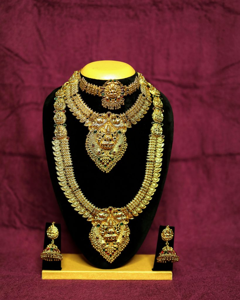 Intricately designed gold necklaces and earrings displayed on a velvet stand, showcasing luxury and craftsmanship.